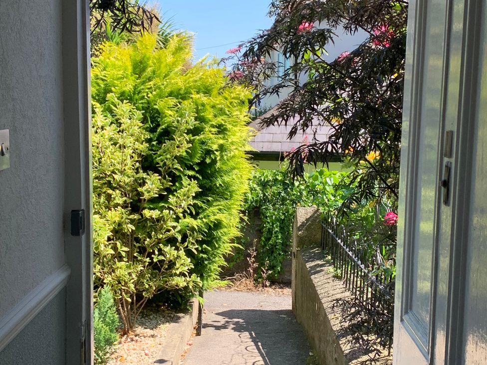 A pathway with bushes and flowers visible from an open door at 3 Newboro Terrace Conwy