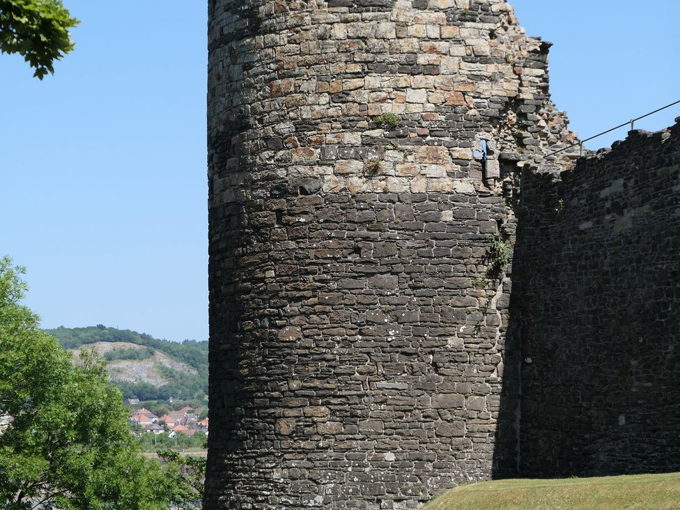 A stone tower with a brick wall and grass at 3 Newboro Terrace in Conwy