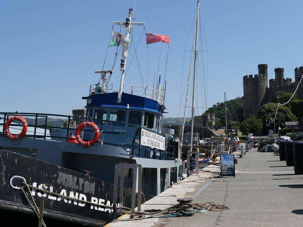 A fishing boat docked at the harbor near a castle at 3 Newboro Terrace in Conwy