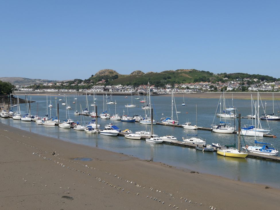 A view of boats docked by the water with hills and houses in the background at 3 Newboro Terrace in Conwy