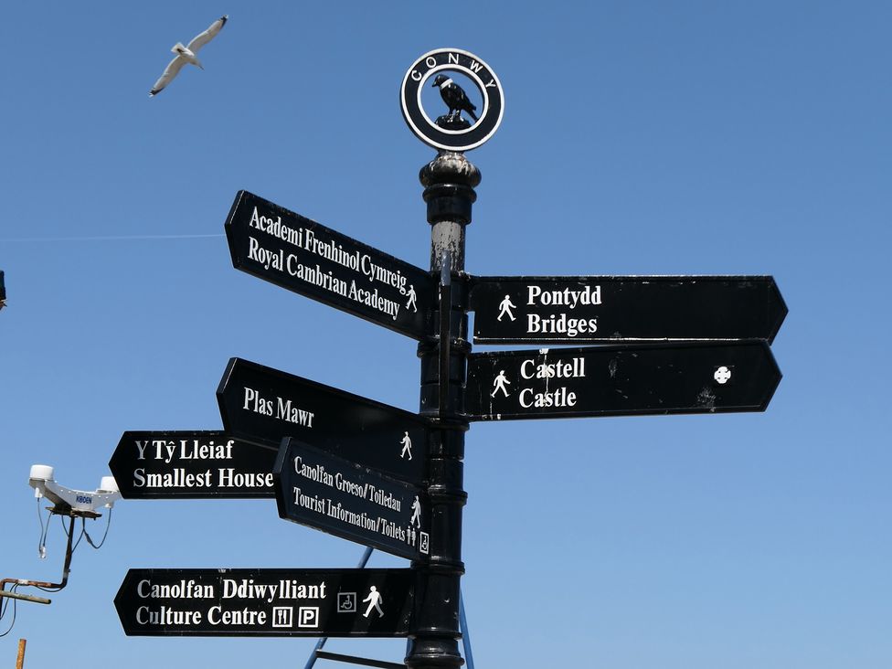A directional signpost with various locations listed at 3 Newboro Terrace Conwy