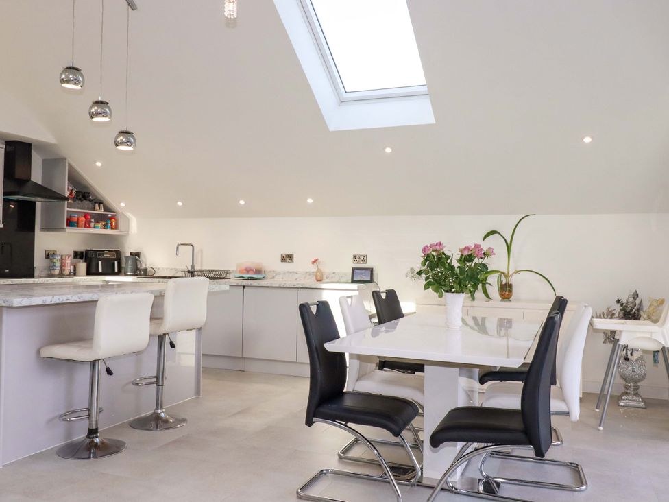 A kitchen with bar stools and a dining table at Meadow Retreat in Bodmin