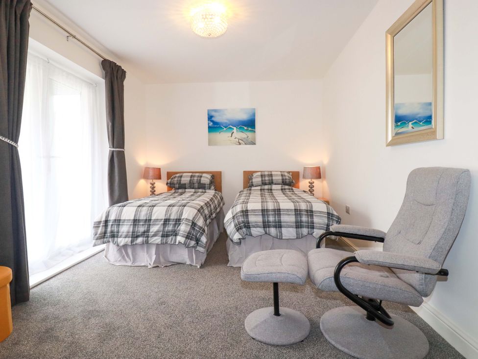 A bedroom with two beds and an armchair at Meadow Retreat in Wadebridge