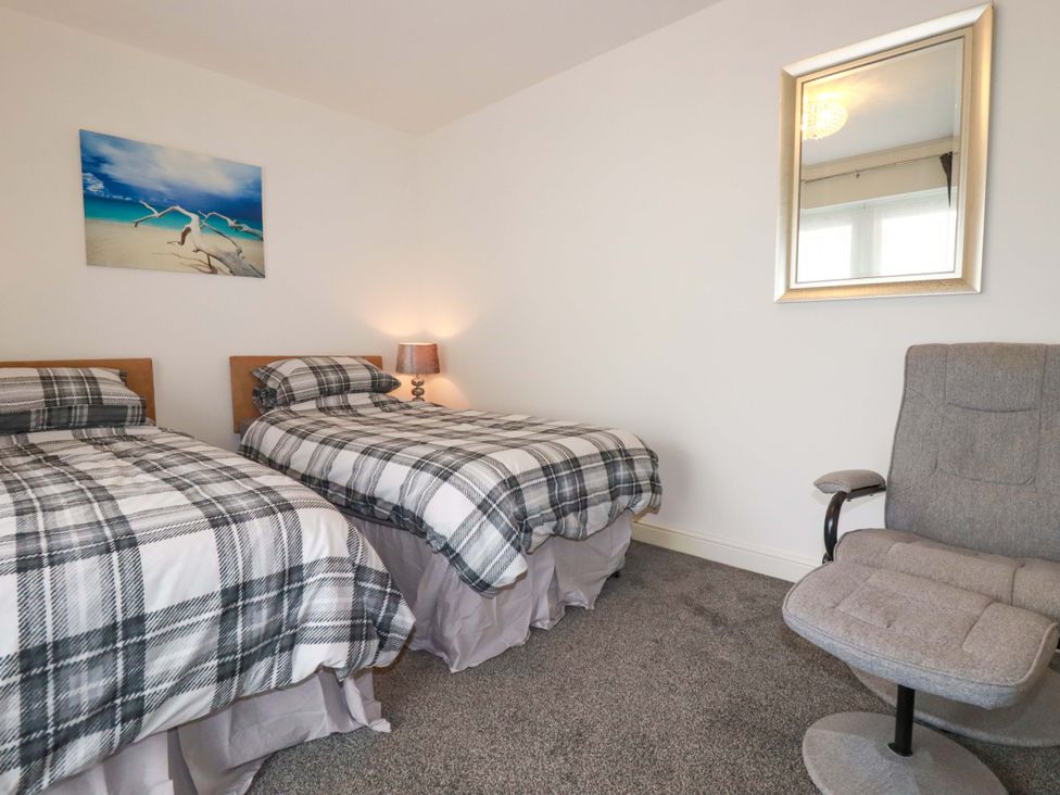 A bedroom with two beds and a chair at Meadow Retreat in Wadebridge