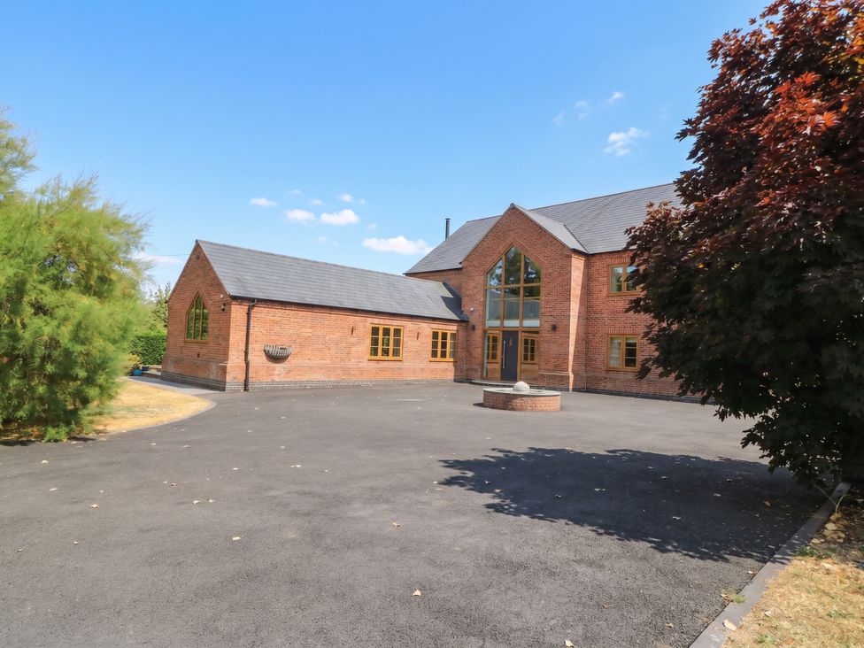 A house with a large driveway and surrounding trees at Hazeldene near Harvington