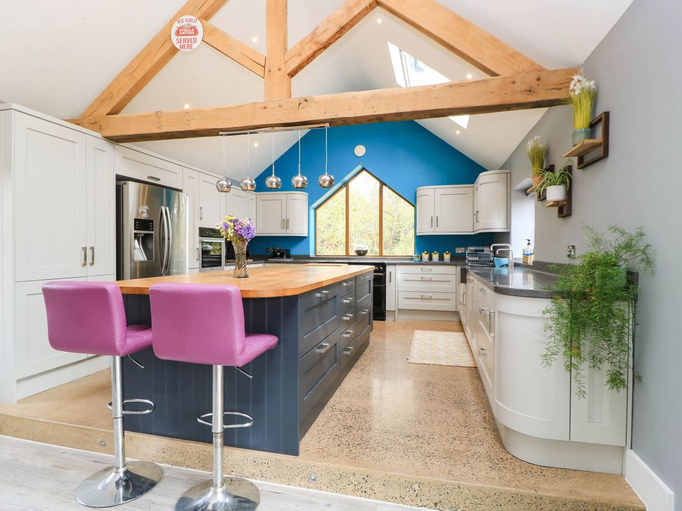 A kitchen with an island and bar stools at Hazeldene near Harvington