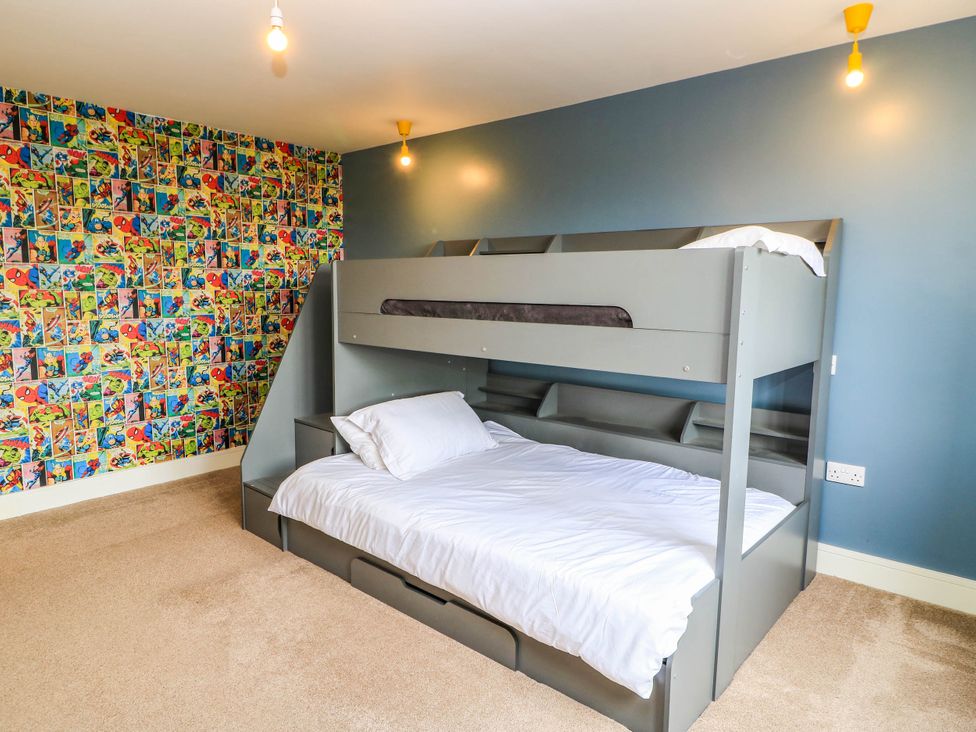 A bedroom with a bunk bed and colorful wallpaper at Hazeldene near Harvington