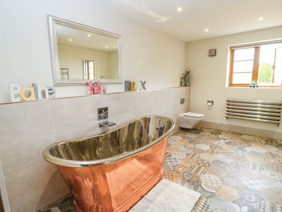 A bathroom with a copper bathtub and a toilet at Hazeldene near Harvington