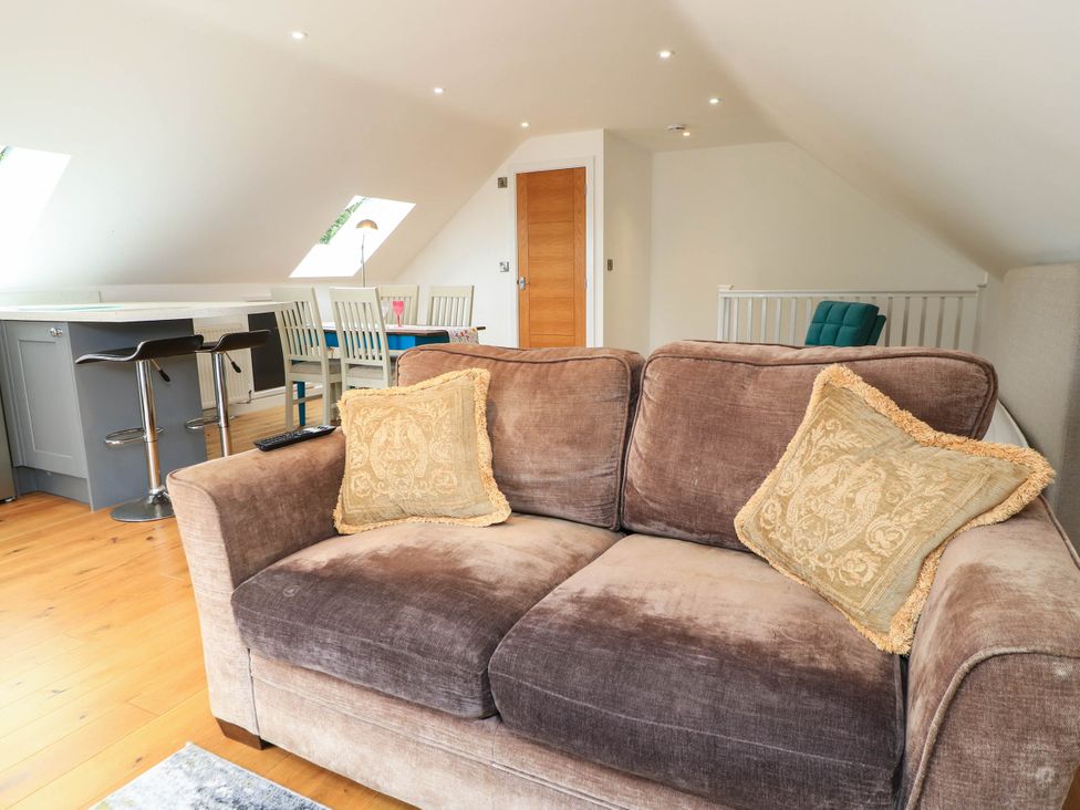A living room with a sofa and dining area at Hazeldene near Harvington