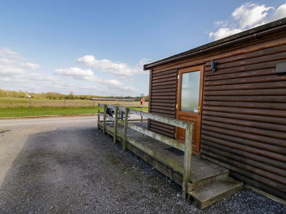 A wooden cabin with a front door and decking at Lavender Lodge in Evesham