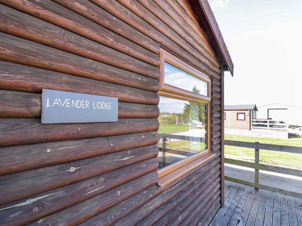 A log cabin exterior with a sign at Lavender Lodge in Evesham