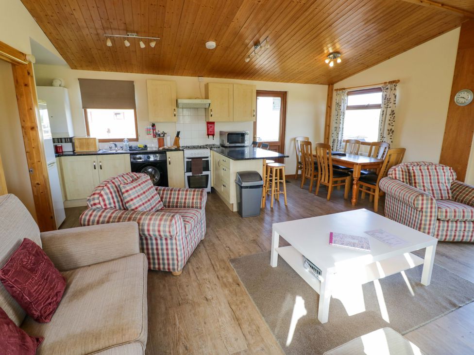 A living room with a dining area and kitchen appliances at Lavender Lodge in Evesham