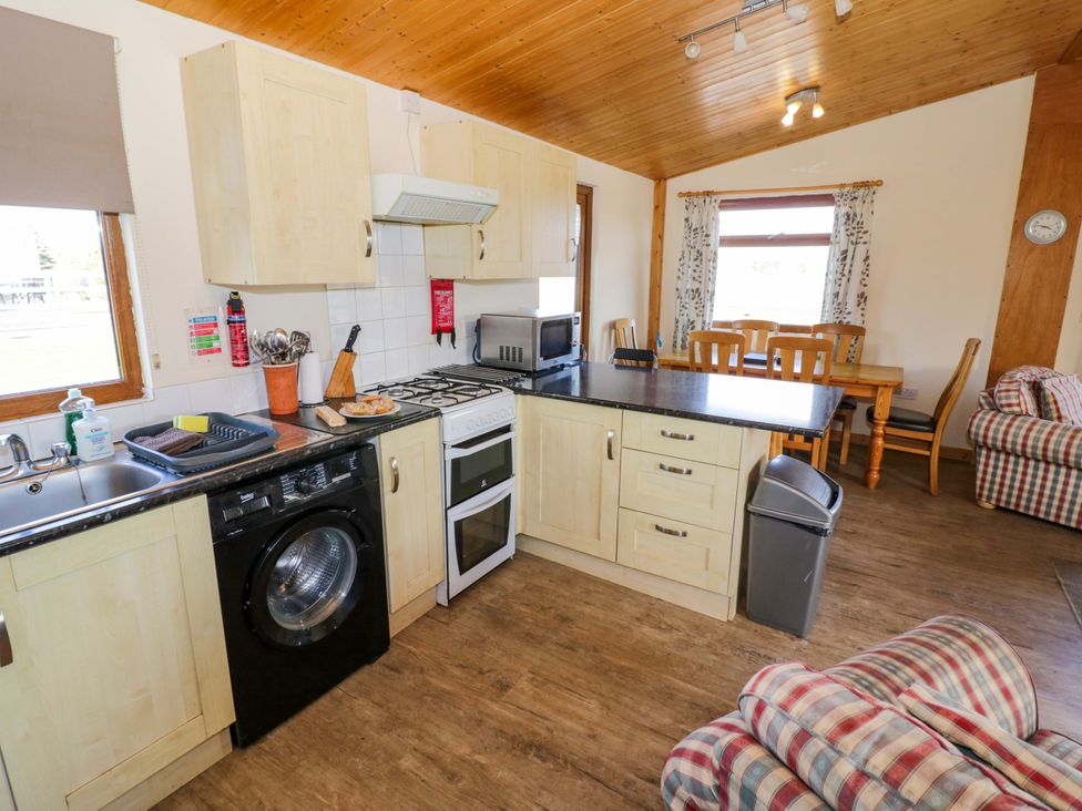 A kitchen with appliances and dining area at Lavender Lodge Evesham