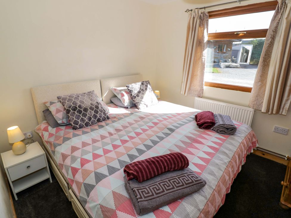 A bedroom with a bed, bedside table and window at Lavender Lodge Evesham