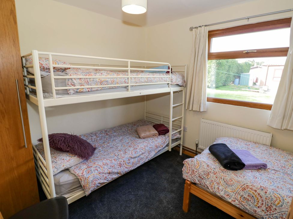 A bedroom with a bunk bed and a single bed at Lavender Lodge in Evesham