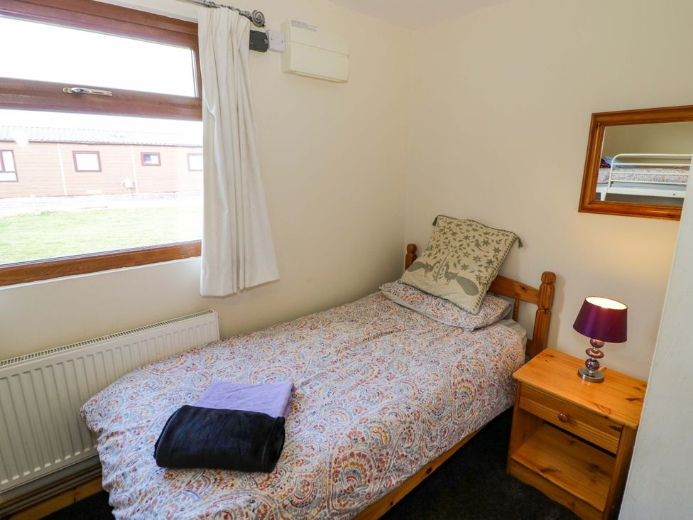 A bedroom with a bed and bedside table at Lavender Lodge Evesham