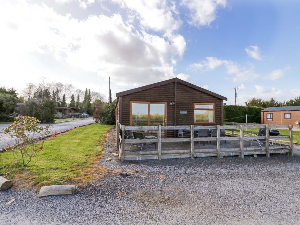 A lodge with a deck and chairs at Lavender Lodge in Evesham