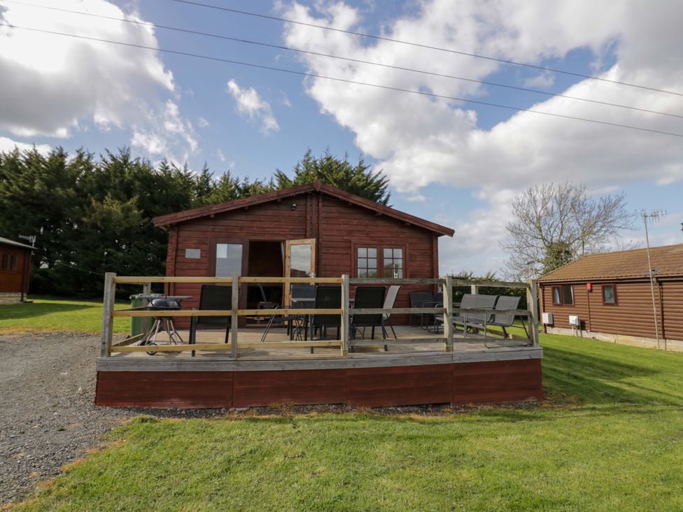 A log cabin with a deck and chairs at Holly Lodge Evesham