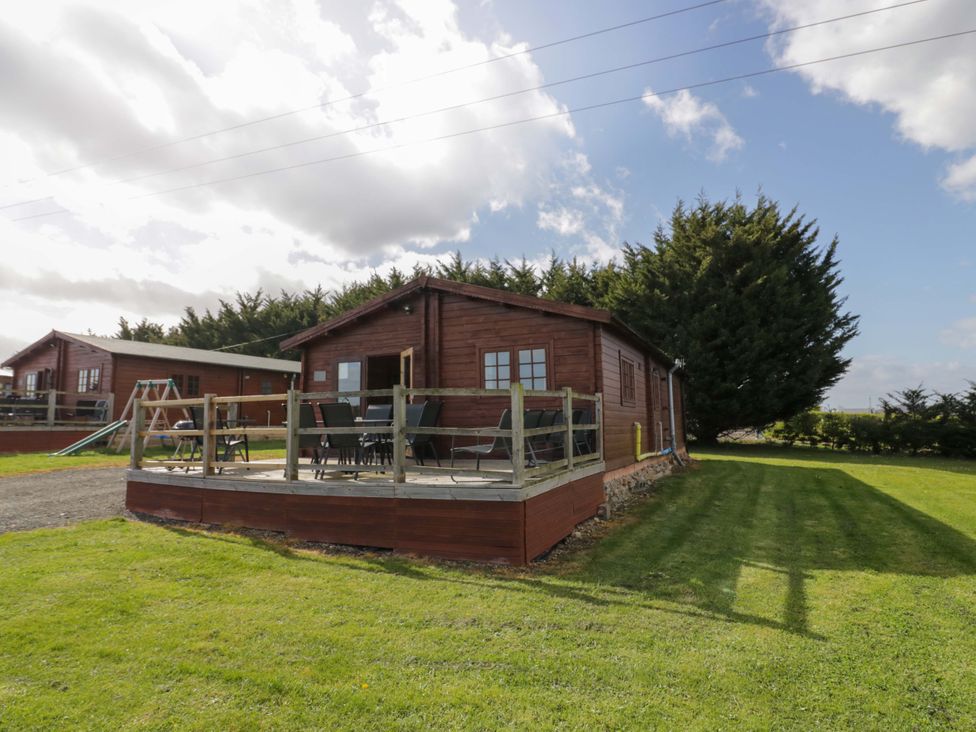 A cabin with a deck and chairs at Holly Lodge in Evesham