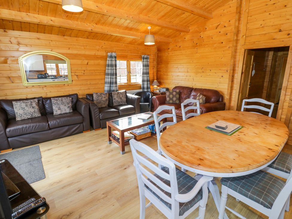 A living room with sofas and a dining table at Holly Lodge Evesham