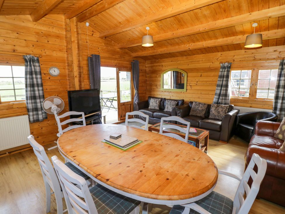 A dining area with a wooden table and sofa at Holly Lodge in Evesham
