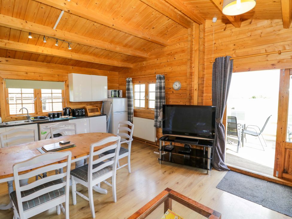 A living room with dining table and kitchen area at Holly Lodge in Evesham