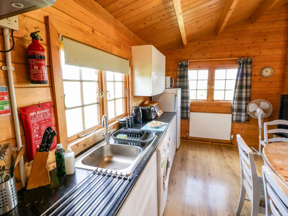 A kitchen with a sink, refrigerator, and dining table at Holly Lodge in Evesham