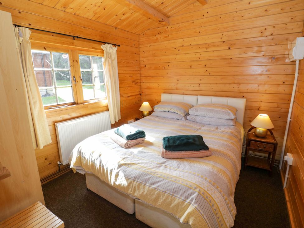 A bedroom with a bed and window at Holly Lodge in Evesham