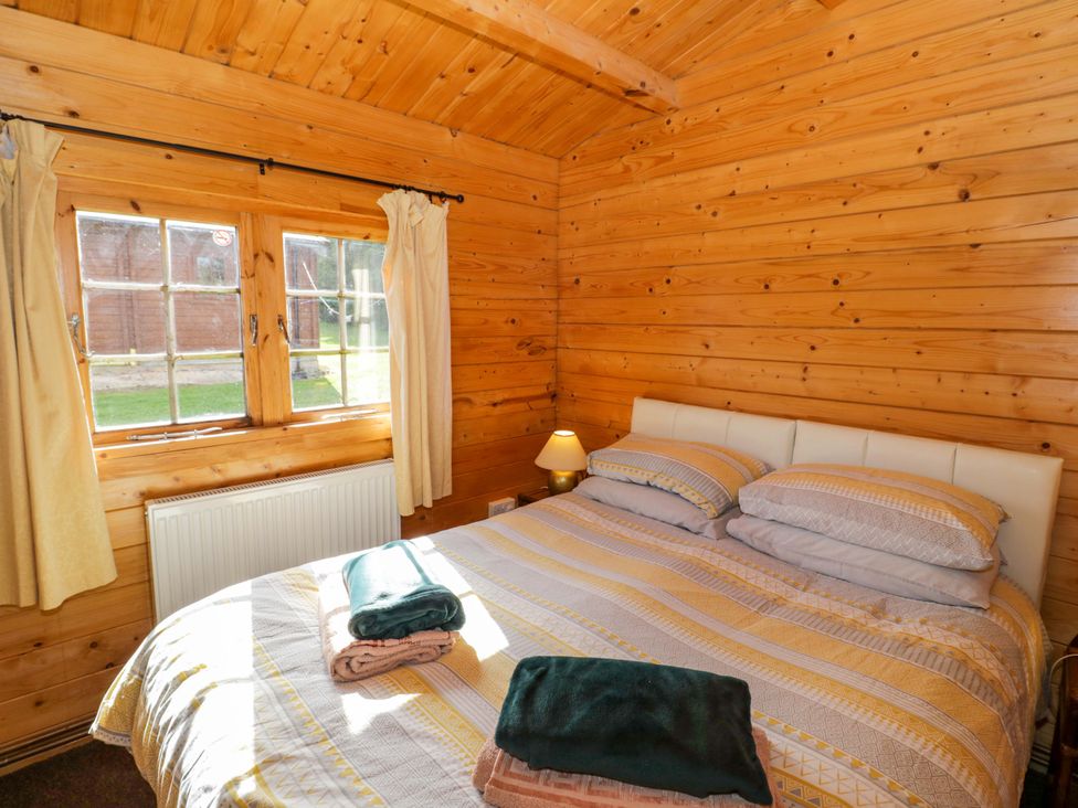 A bedroom with a double bed and window at Holly Lodge in Evesham