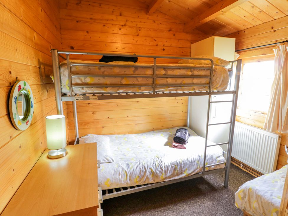 A bedroom with a bunk bed and a single bed at Holly Lodge in Evesham