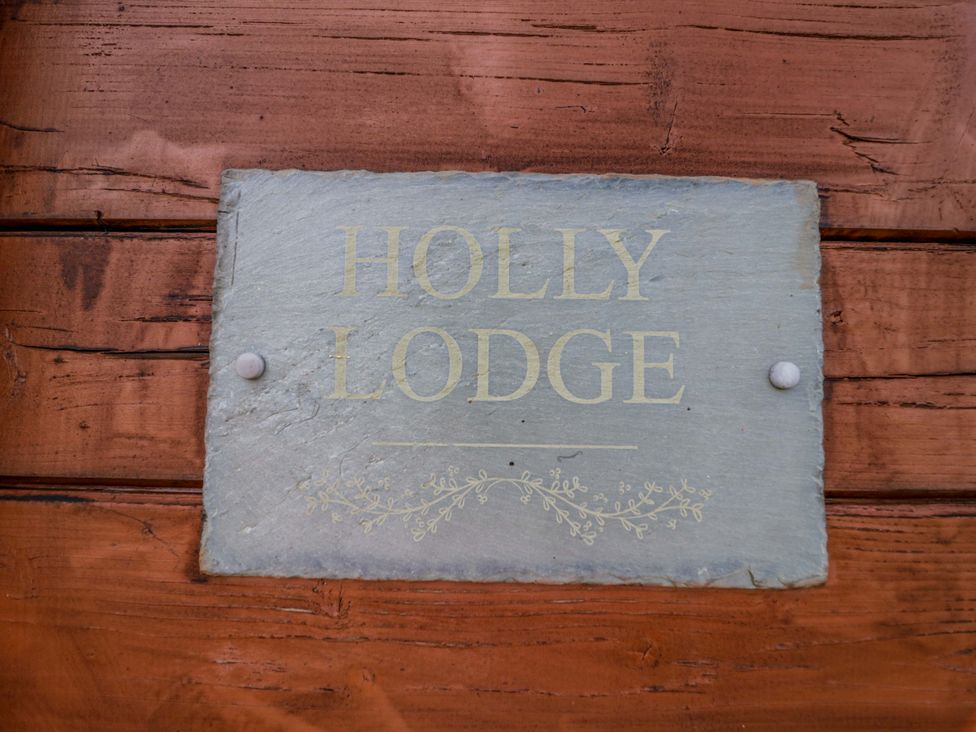 A sign reading HOLLY LODGE attached to wooden surface at Holly Lodge in Evesham