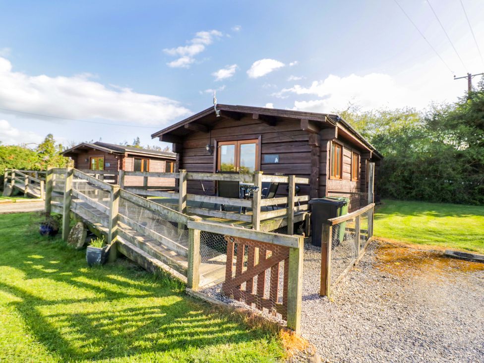 A log cabin with a fence and decking at Primrose Lodge Offenham