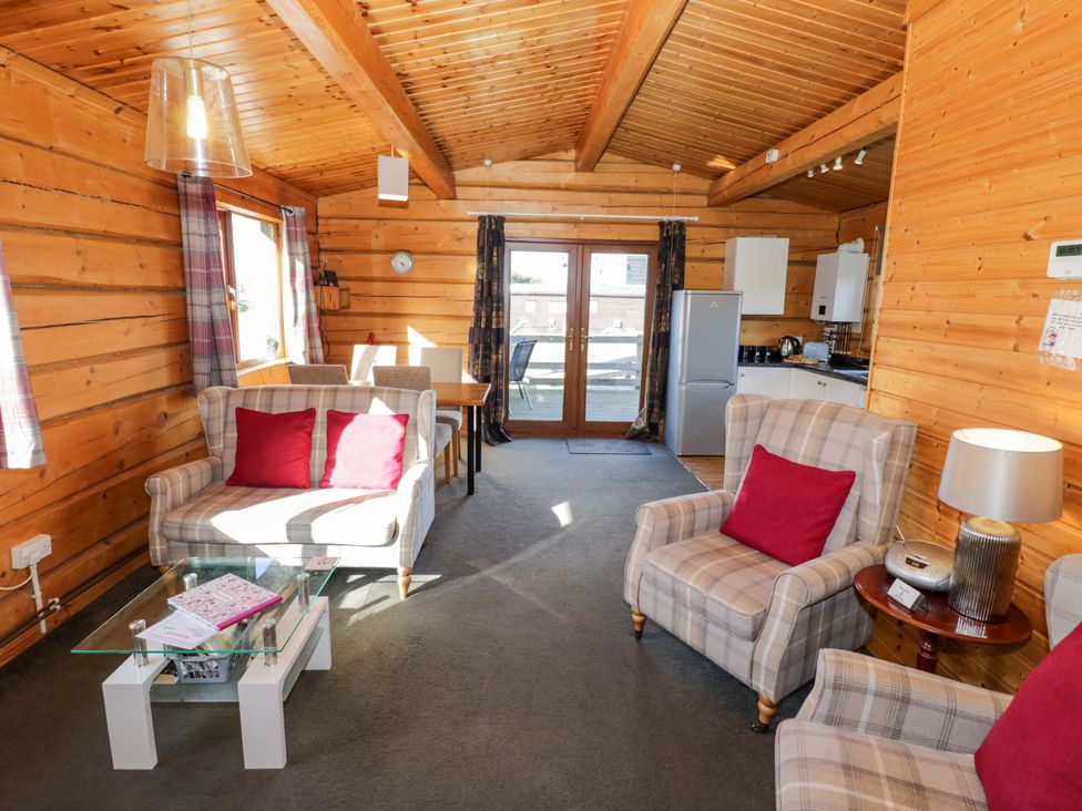 A living room with sofa and dining area at Primrose Lodge Offenham