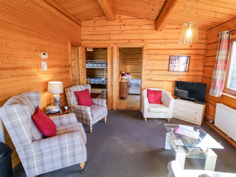 A living room with armchairs and a television at Primrose Lodge Offenham