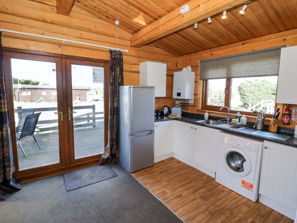 A kitchen with appliances and a door leading outside at Primrose Lodge Offenham