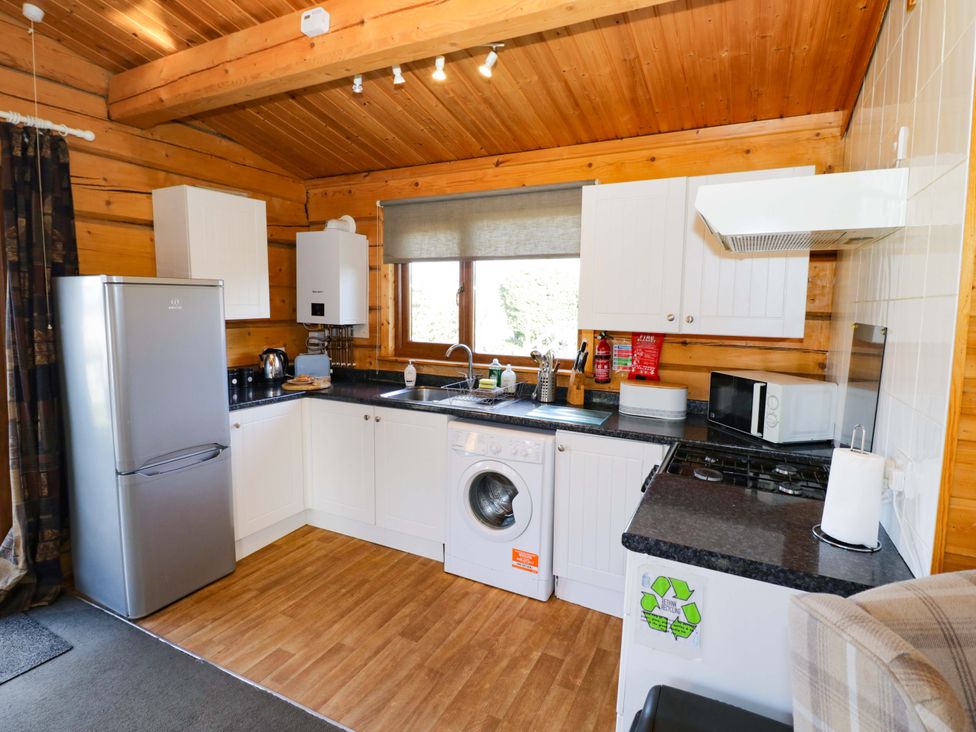 A kitchen with appliances including a refrigerator and washing machine at Primrose Lodge Offenham