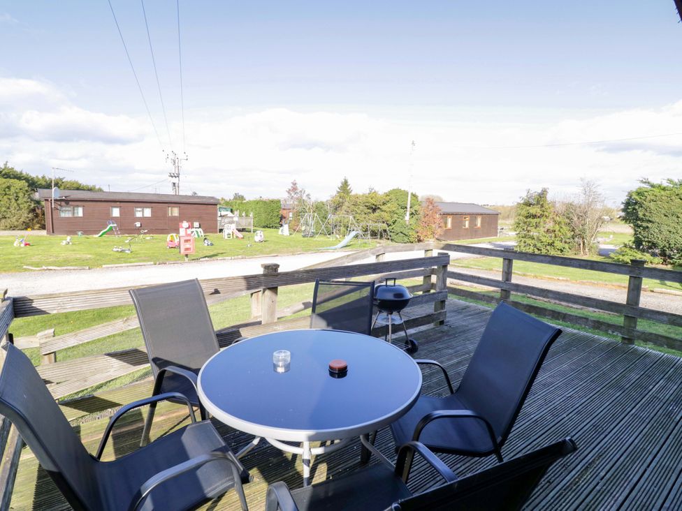 An outdoor seating area with a table and chairs at Primrose Lodge Offenham