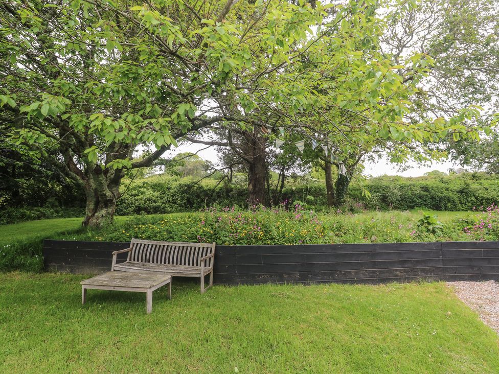 A garden with a wooden bench and trees at Birdsong in Gulval