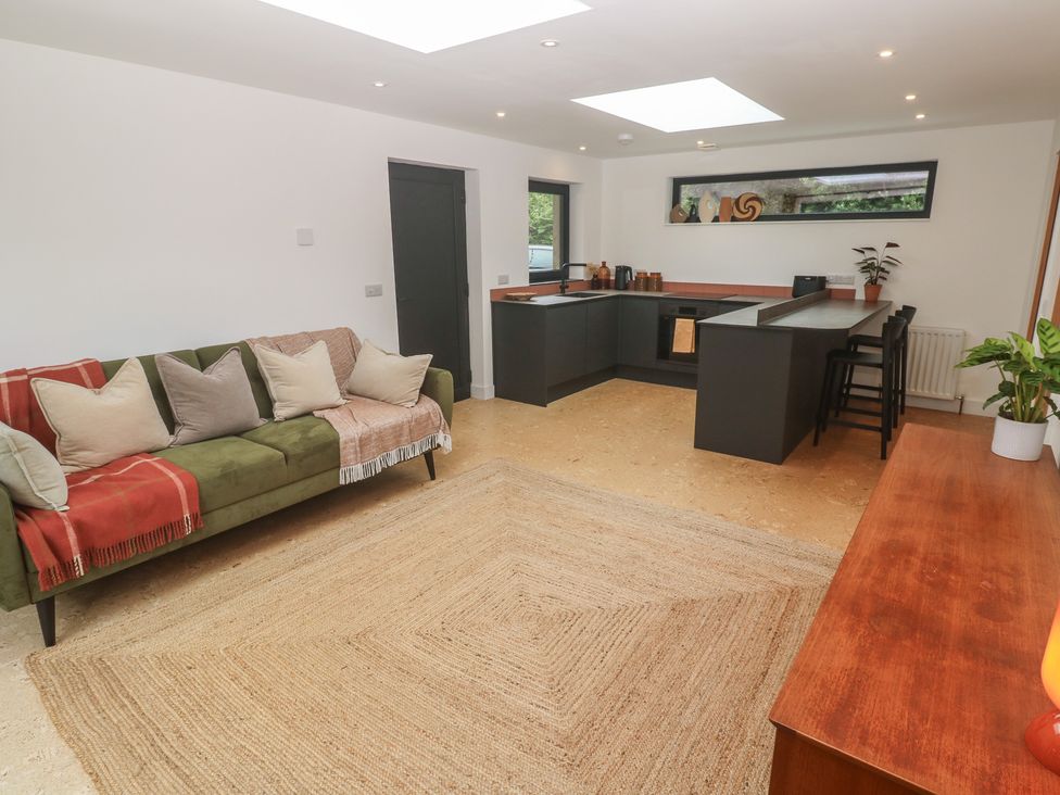 A living room with a sofa and kitchen area at Birdsong in Gulval