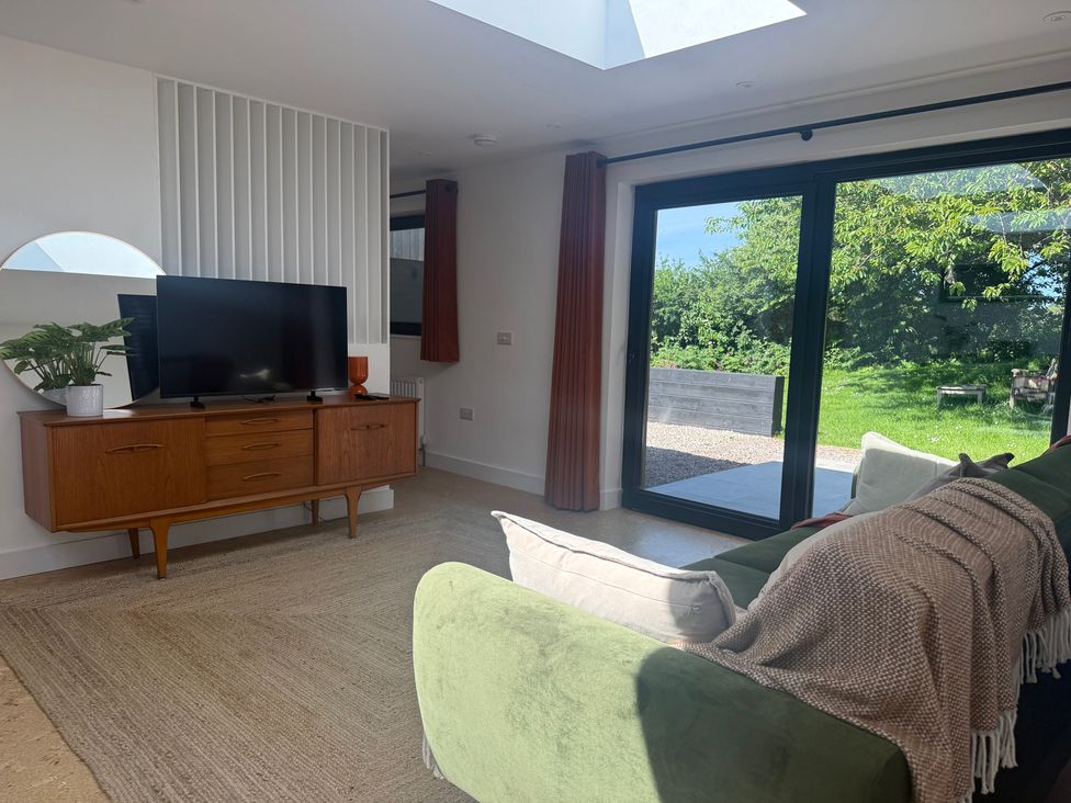A living room with a television and sliding doors at Birdsong in Gulval