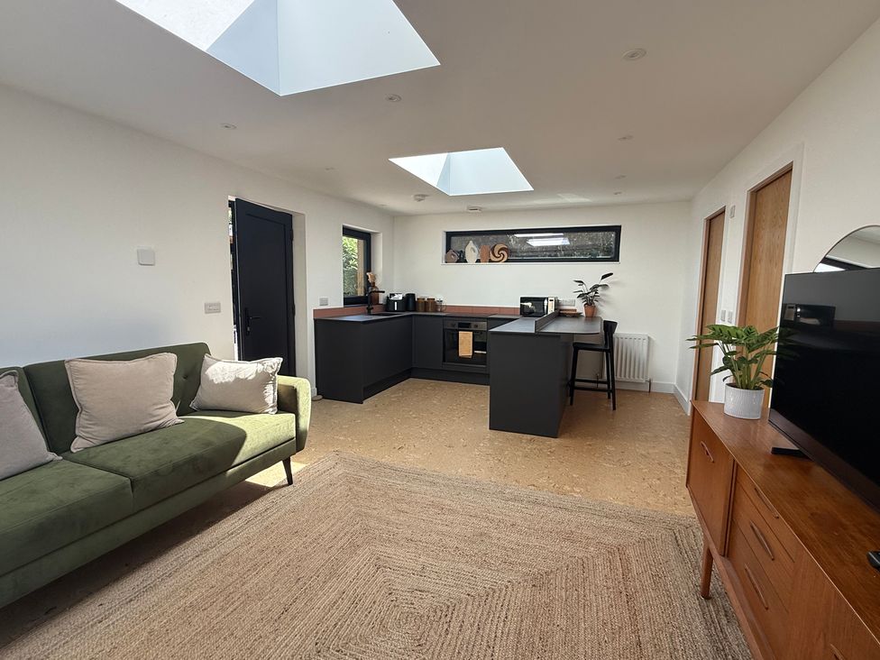 A living room with a kitchen and a sofa at Birdsong in Gulval