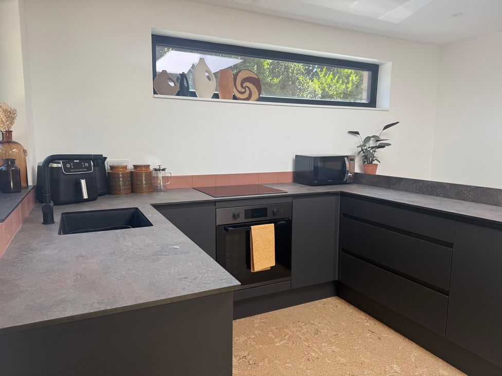 A kitchen with a sink, microwave and air fryer at Birdsong in Gulval
