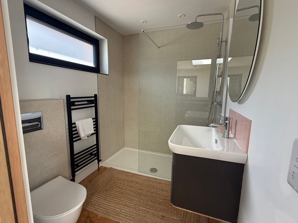 A bathroom with a shower, toilet, sink and towel rack at Birdsong in Gulval