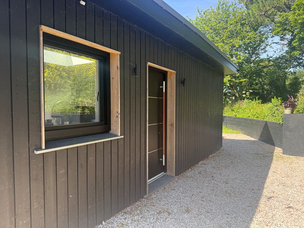An exterior view of a black wooden building with a door and window at Birdsong in Gulval