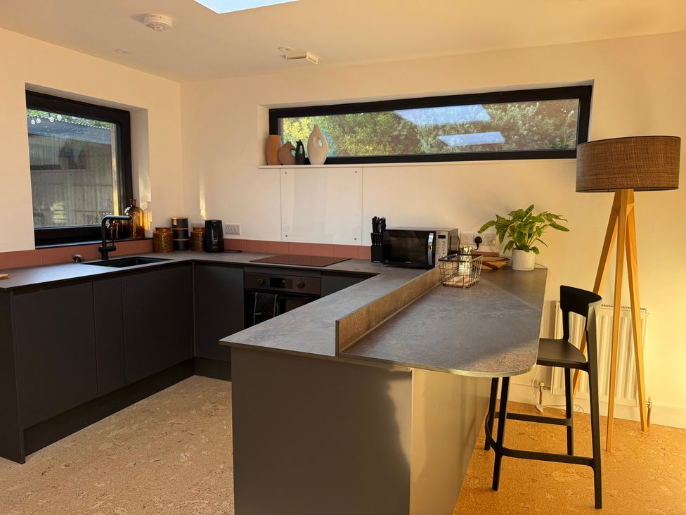 A kitchen with a countertop and bar stools at Birdsong in Gulval