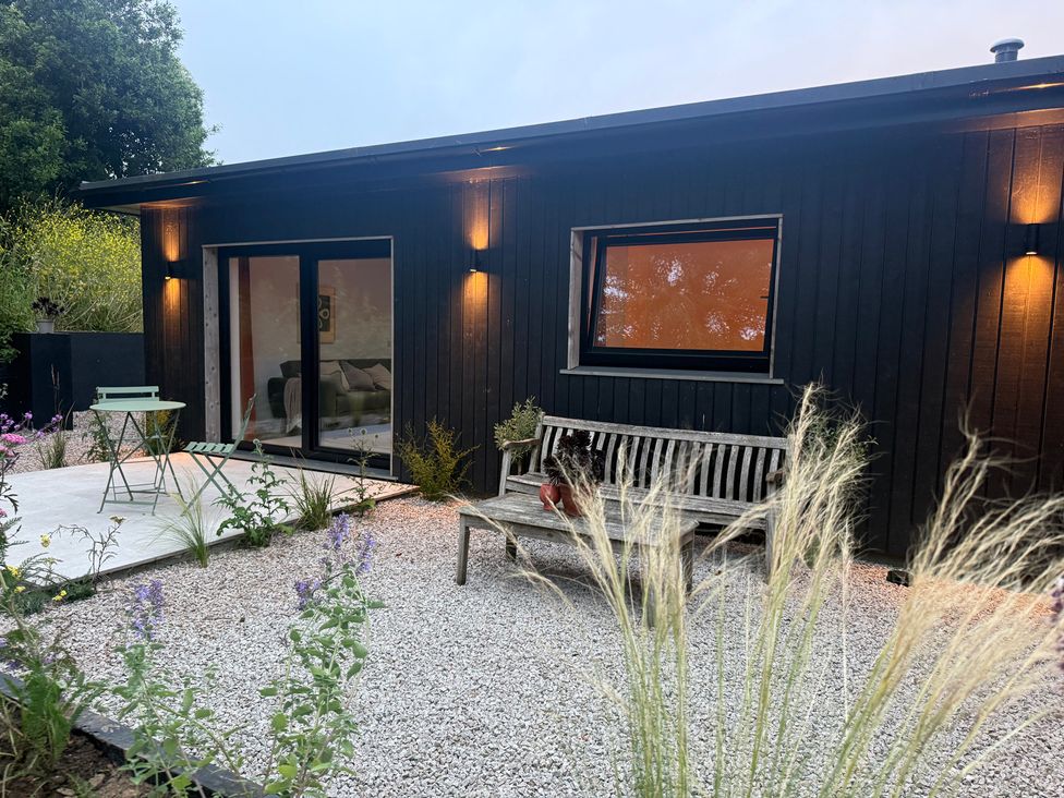 An outdoor seating area with a bench and table at Birdsong in Gulval