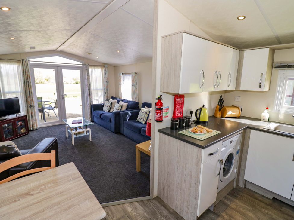 A living room with a sofa, TV and kitchen appliances at Laurel Lodge Offenham