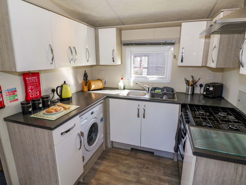 A kitchen with a washing machine and stove at Laurel Lodge, Offenham
