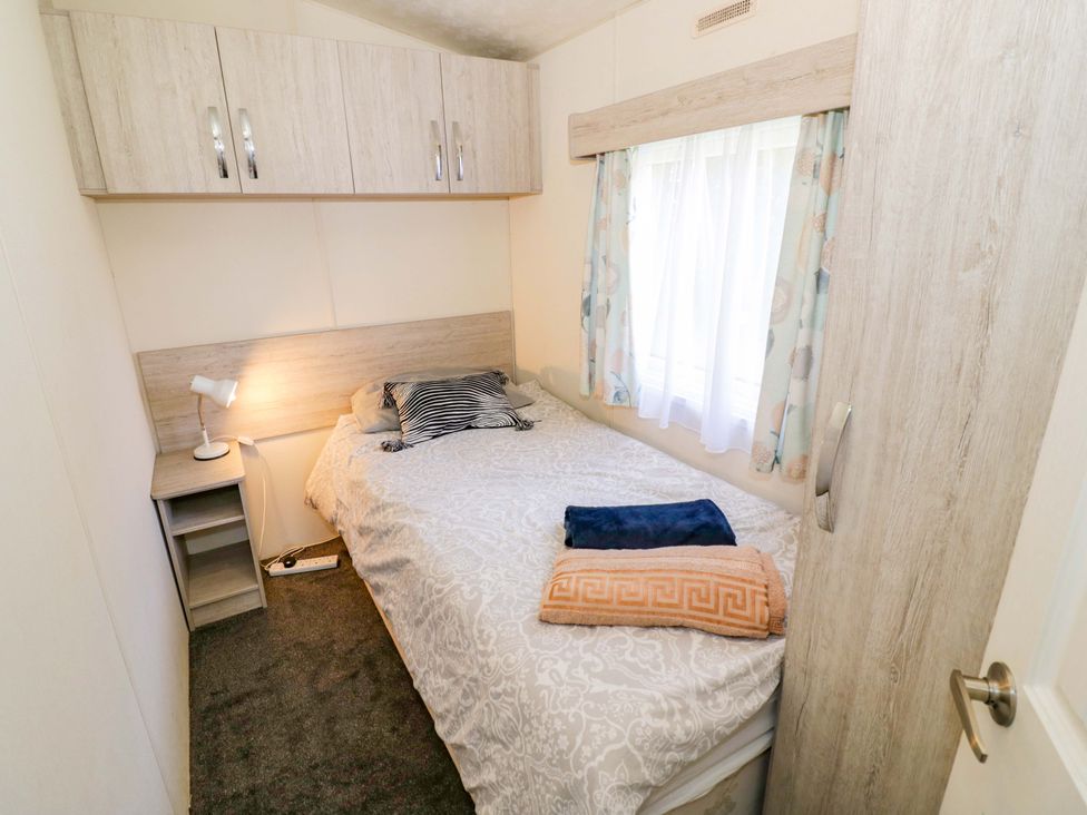 A bedroom with a bed and bedside lamp at Laurel Lodge in Offenham