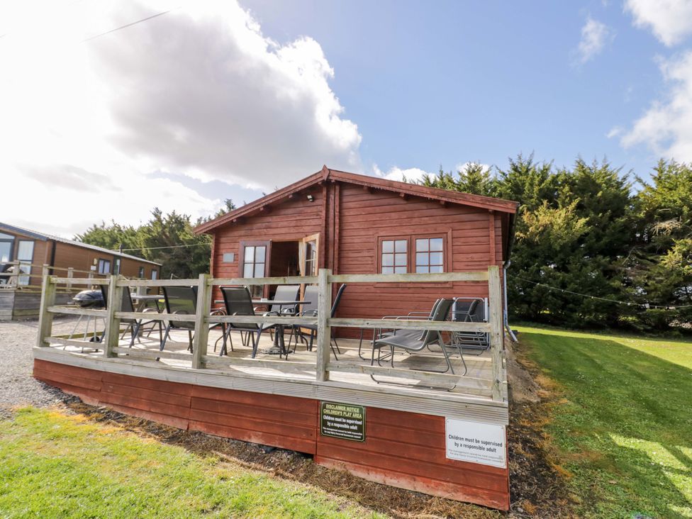 A lodge with a deck and chairs at Oak Lodge Offenham